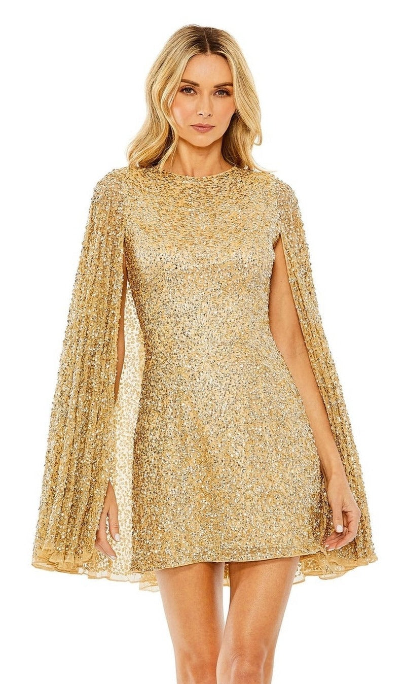 A woman models the Mac Duggal 5931 Short Gold Beaded Cocktail Dress with cape sleeves, standing against a plain white background.